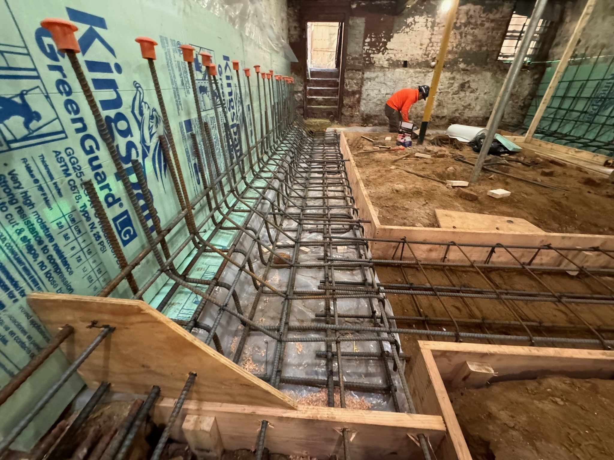 Worker preparing foundation reinforcement and formwork